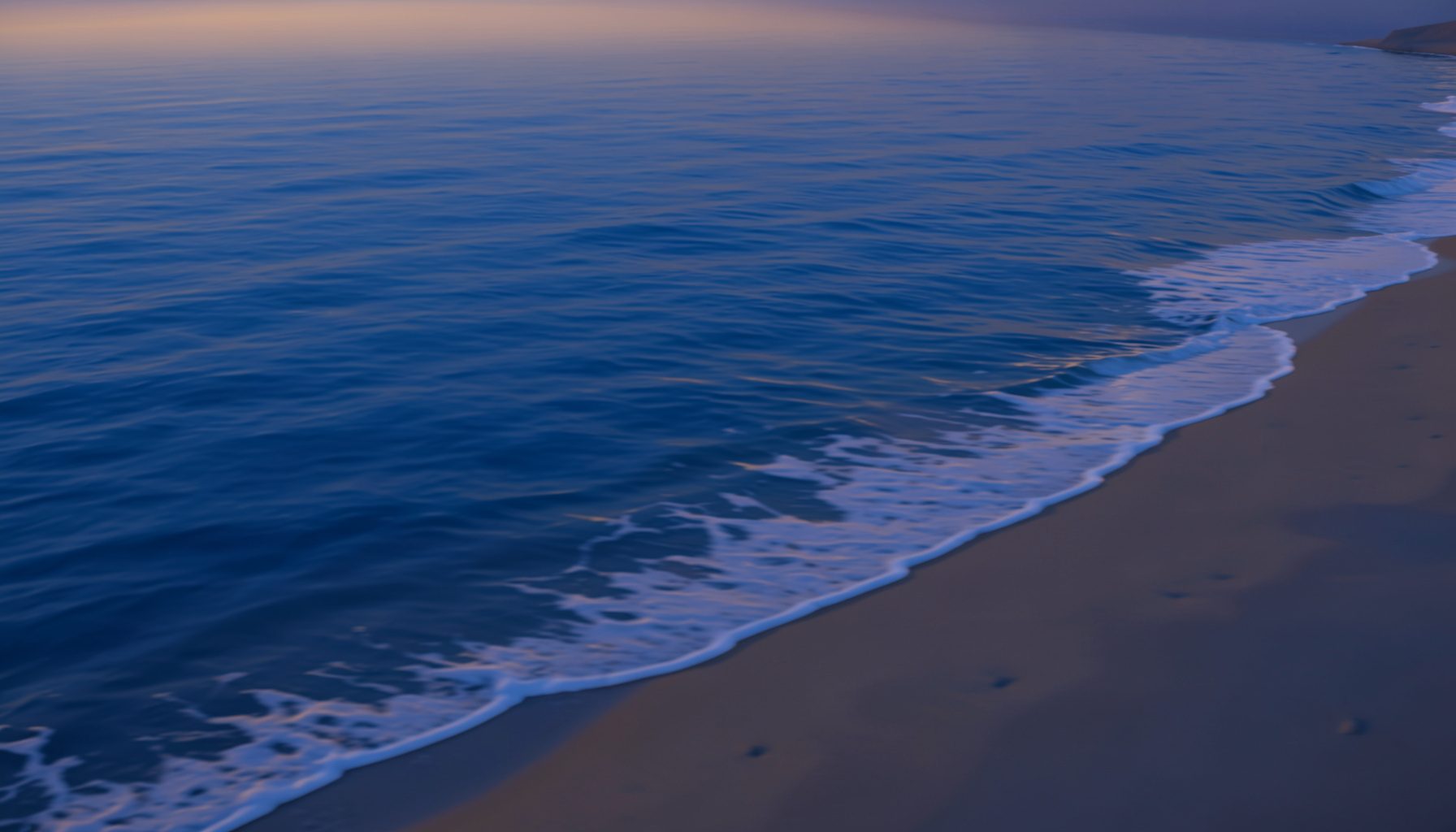A calm ocean shoreline at dusk with gentle waves rolling onto sandy beach, soft blue and golden tones